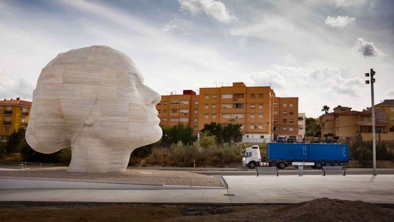 Un camion en phase de test passe devant une statue de marbre en Espagne